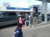 Gabriella gives a packet to a man at a gas station.